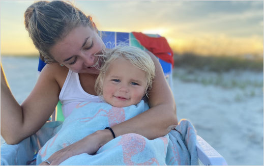 A mother and her child sitting in a chair on the beach